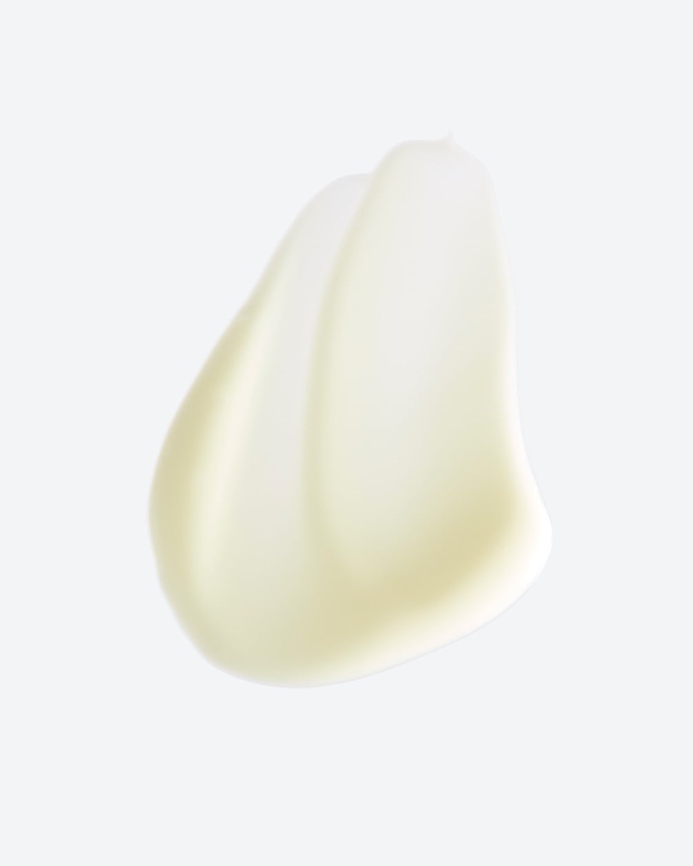 Texture swatch of a creamy, light-yellow serum. The product is shown as a smooth, layered vertical smear against a white background.