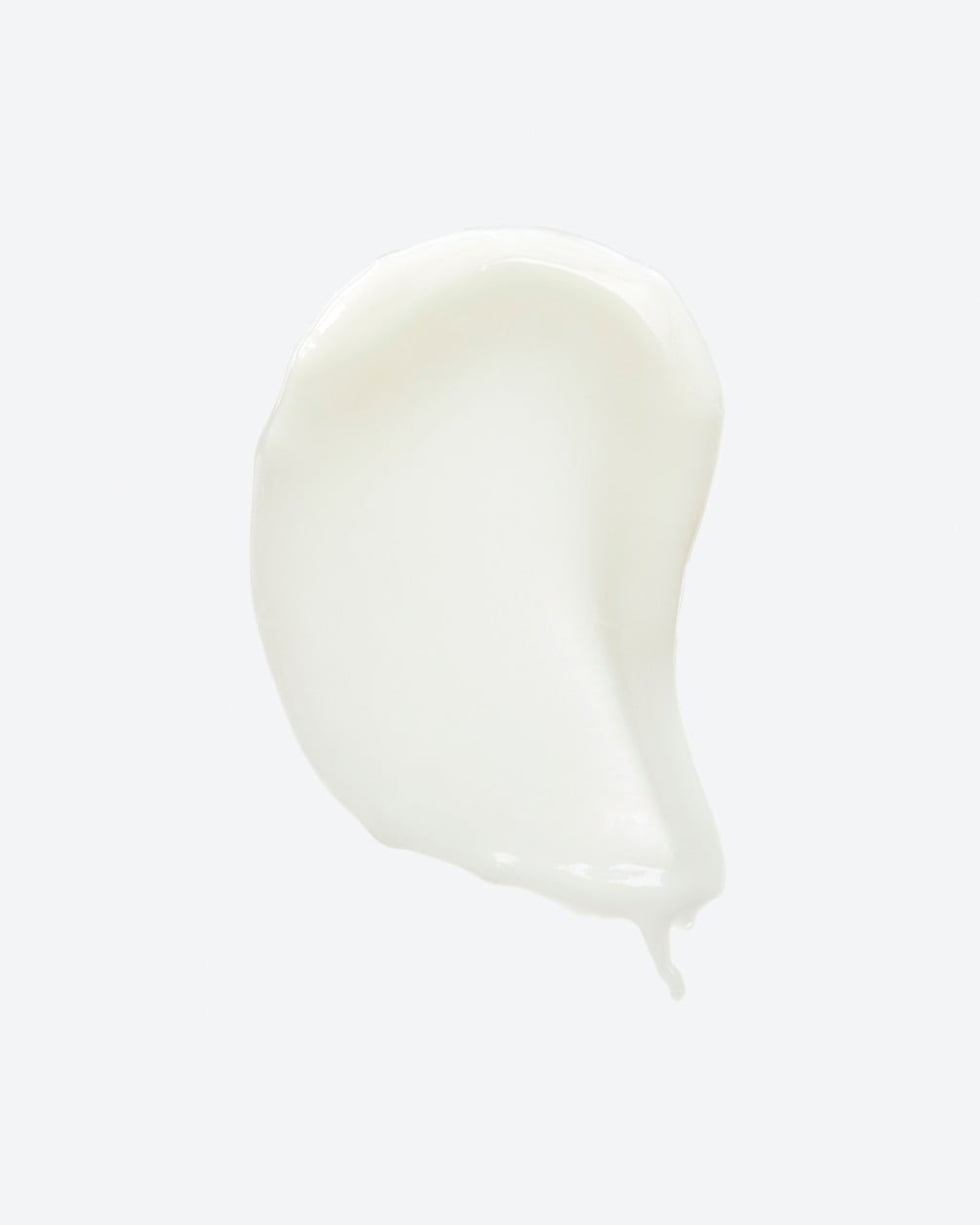 A texture swatch of a thick, opaque white skincare cream or serum. The product is shown as a smooth, vertical smear against a plain white background, featuring a rounded top and a slightly tapered tail at the bottom.