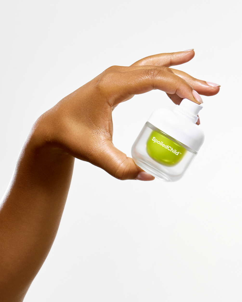 A person's hand with manicured nails holding a small, frosted SpoiledChild T31 jar with a lime-green refill capsule inside, positioned against a plain white background.