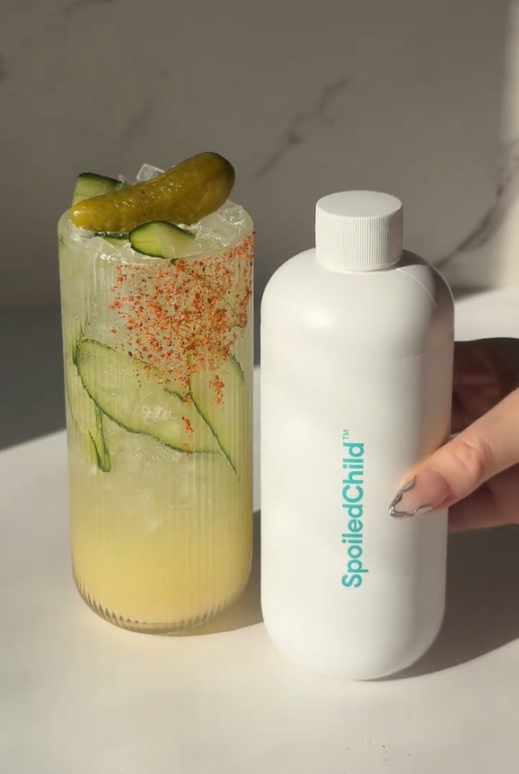 Savory pickle magnesium refresher over ice in a chili-rimmed glass with cucumber slices and a pickle garnish