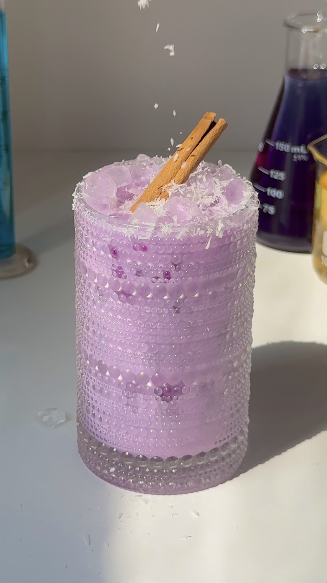 Glass of creamy purple ube collagen horchata over ice with a cinnamon stick and salted rim